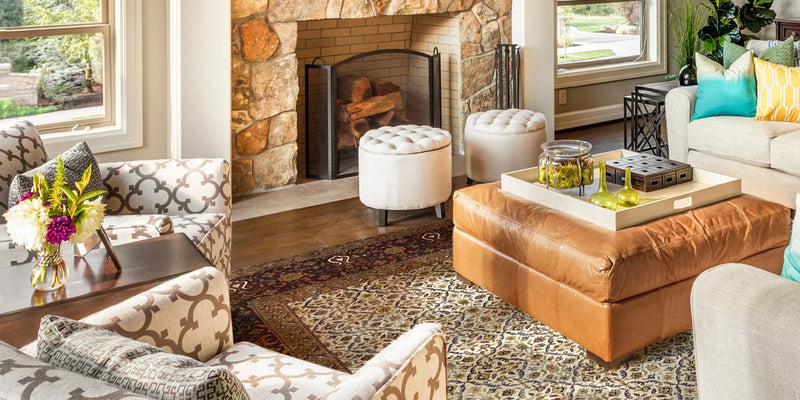 living room with rug in front of fireplace next to leather poof and chairs
